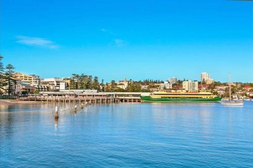 a large green boat on a large body of water at Manly Vibes - fabulous design with gym, sauna, streaming, right opposite wharf & beach in Sydney