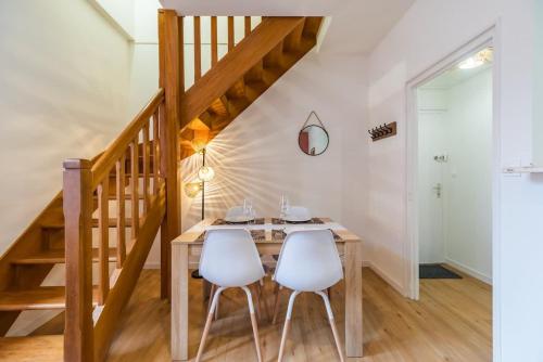 a dining room with a wooden table and two white chairs at Charmant Duplex avec jacuzzi Guingamp centre in Guingamp