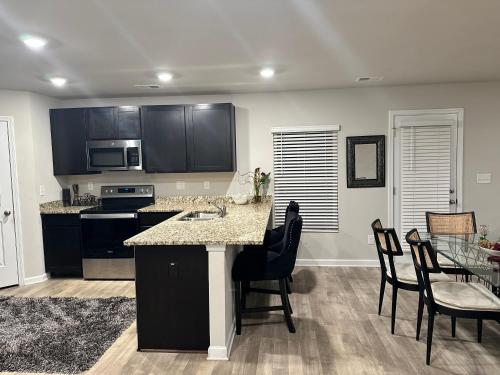 a kitchen with black cabinets and a table and chairs at Exquisite 5 Bedroom Near Airport in Ellenwood