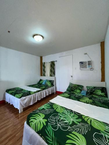 two beds in a room with green and white sheets at Isla Paraiso Resort-Hotel in Sison