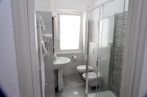 a white bathroom with a toilet and a sink at Appia Antica Guest House in Rome