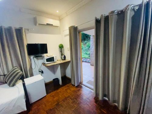 a room with a bed and a door with a television at Caribe Accommodation and Conferences in Pietermaritzburg