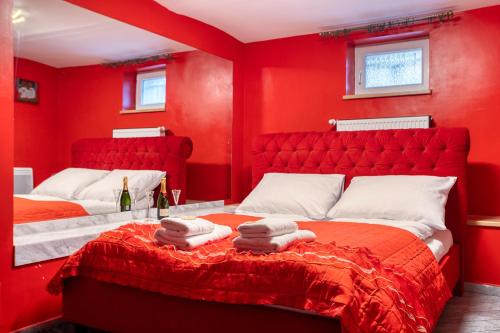 een rode slaapkamer met 2 bedden en rode muren bij Apartamenty Firfas 2 in Bydgoszcz