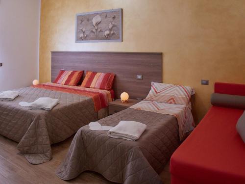 a hotel room with two beds and a red couch at BnB Anna e Leo - Casa di Anna in Pietra Montecorvino