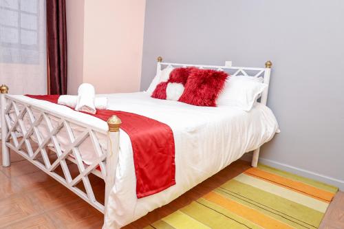 un letto bianco con cuscini rossi e bianchi di 2 bedroom Stylish Apartment, Kisumu a Kisumu
