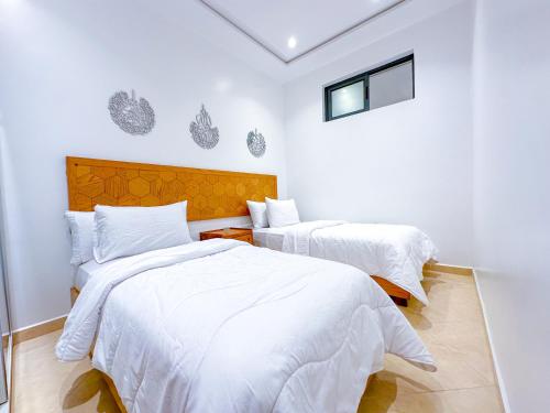 two beds in a room with white walls at Luxury of Mesnana - Stay with low budget in Tangier