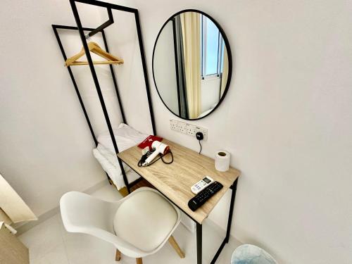 a mirror on a wall next to a table and a chair at Stylish Cozy Landed Jelutong 3Room2bath4park 10pax in Jelutong