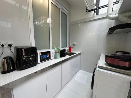 a white kitchen with a sink and a microwave at Stylish Cozy Landed Jelutong 3Room2bath4park 10pax in Jelutong