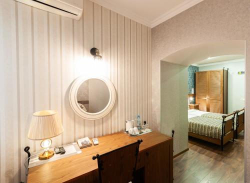 a room with a desk with a bed and a mirror at Wine Story Hotel in Tbilisi City