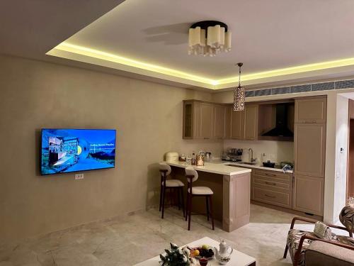 a living room with a kitchen with a tv on the wall at Sea Breez The Grant Hotel Apartment in Bilgah