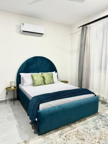 a bed with a blue headboard in a bedroom at Azure 4bdrm beachfront at jumeirah palm resort nyali in Bamburi