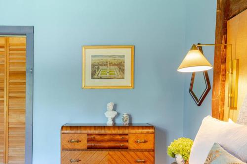 a bedroom with a blue wall with a dresser and a lamp at Unique Fully Restored Landmark Barn in Hudson in Claverack