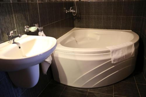 a bathroom with a tub and a toilet and a sink at Хотел Кипарис, Враца in Vratsa
