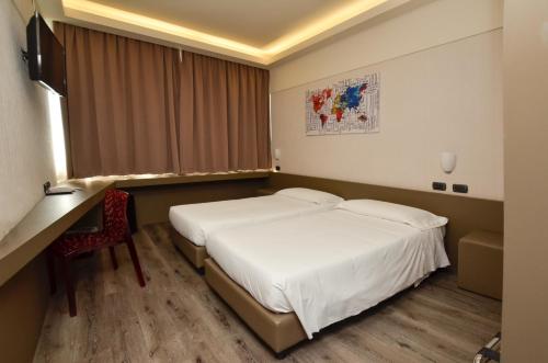 a hotel room with two beds and a desk at The Gate Hotel - Firenze Nord in Sesto Fiorentino