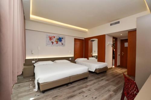 two beds in a hotel room with wooden floors at The Gate Hotel - Firenze Nord in Sesto Fiorentino