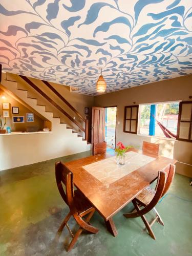 a dining room with a table and a blue and white patterned ceiling at Adios Amigos Hostel in Arraial d'Ajuda
