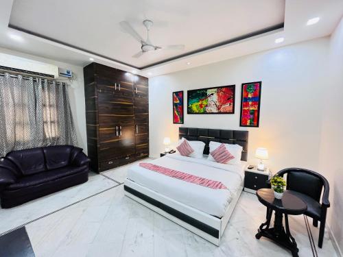 a bedroom with a large bed and a black chair at South Inn - Green Park South Delhi in New Delhi