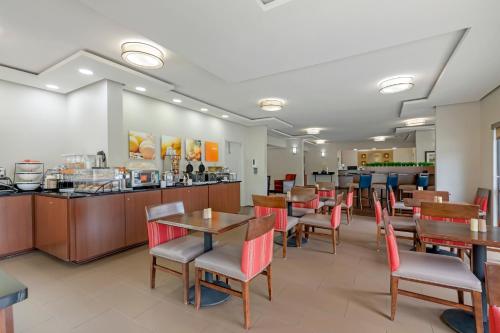 a restaurant with tables and chairs and a counter at Comfort Inn & Suites Covington - Mandeville in Covington