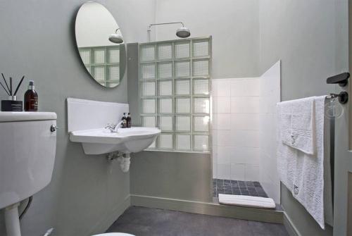 Un baño blanco con lavabo y espejo. en Two Penguins, en Ciudad del Cabo