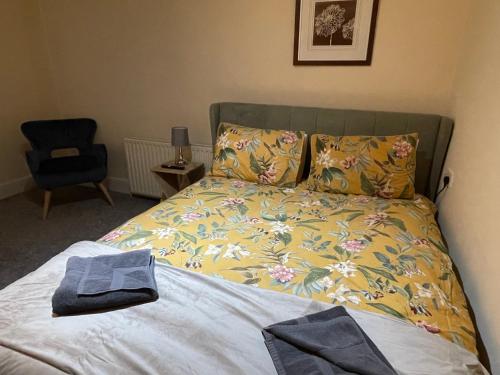 a bedroom with a bed with a blanket and a chair at The Coach House at The Bull Inn in Milton Keynes