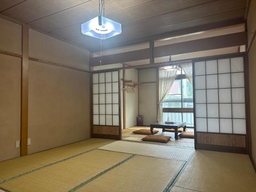 an empty room with a chandelier and a room with a table at 苗場ウッドインだいまる in Yuzawa