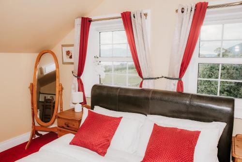 a bedroom with a bed with red curtains and a mirror at Seaview Guesthouse in Rostrevor