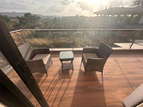 a balcony with chairs and a table and a view at Woods by Mizzle Exotica Premium Villas in Lonavala