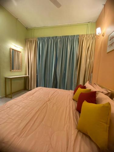 a bedroom with a white bed with yellow and red pillows at Seri Idaman Room and Studio - MusIim Only in Kampong Gaung