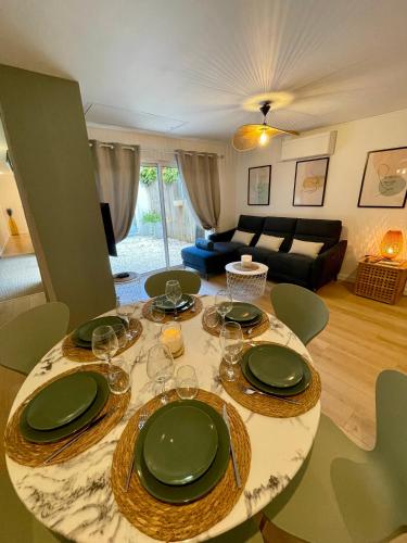 a dining room table with green plates and wine glasses at Patio - 2min gare - Local velos motos - clim in Bordeaux