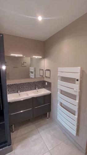 une salle de bain avec deux lavabos et un grand miroir dans l'établissement Grande maison tout confort 24 h - jardin et calme, à Voivres-lès-le-Mans