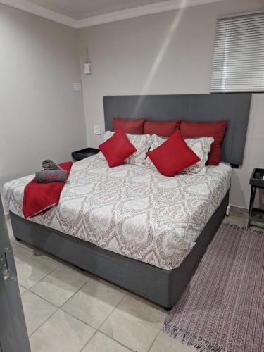 a bedroom with a large bed with red pillows at 9 Levubu Cottages in Polokwane