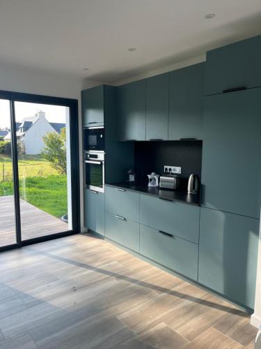 une cuisine avec des armoires noires et une grande porte coulissante en verre dans l'établissement Port lenn, à Arzon