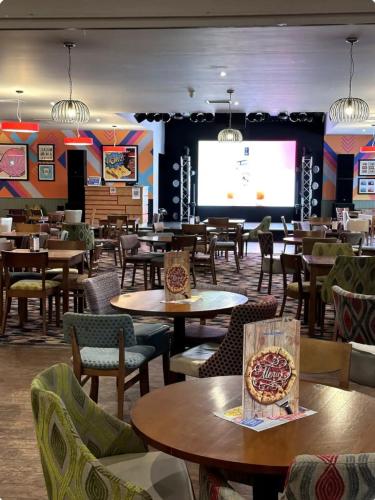 a restaurant with tables and chairs and a projection screen at Beatrice homes in Parkeston