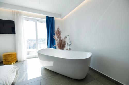 a white bathroom with a tub and a bed at Flamingo Hotel Malta in St Julian's