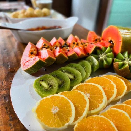 Ein Teller mit Früchten, darunter Orangen und Kiwis, stand auf einem Tisch. in der Unterkunft Sonhos de Penha - Guest House in Penha