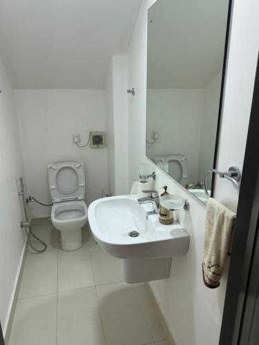 a white bathroom with a toilet and a sink at Templers square in Attidiya