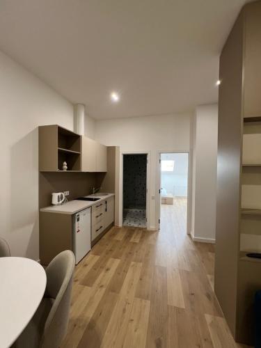 a kitchen with white cabinets and a table and wooden floors at Apartment suite Mukachevo in Mukacheve