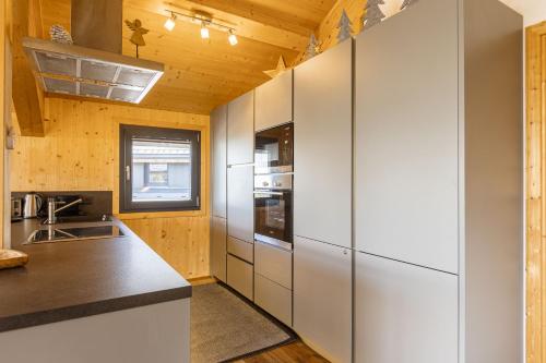 a kitchen with white appliances and a wooden ceiling at Alpenchalets Reiteralm by ALPS RESORTS in Schladming