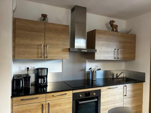 - une cuisine avec des placards en bois et des appareils noirs dans l'établissement Super appartement moderne 2 chambres avec balcon, parking et Wi-Fi - 6 pers. - FR-1-676-195, à Châtel
