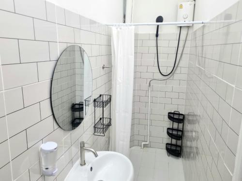 a white tiled bathroom with a sink and a mirror at Haus Sathorn Pier 2 Cozy Bedroom City Center in Bangkok
