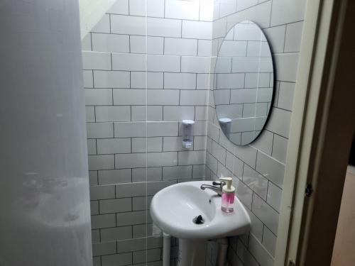 a white bathroom with a sink and a mirror at Haus Sathorn Pier 2 Cozy Bedroom City Center in Bangkok