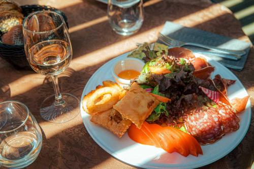 a plate of food on a table with a glass of wine at Logis Hotel Eden Lac in Savines