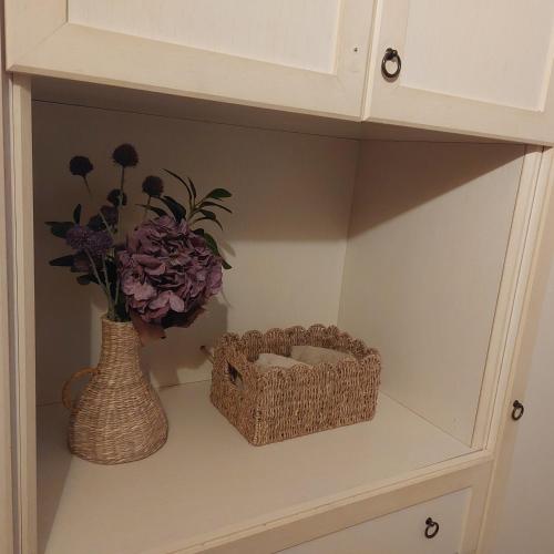 a shelf with a basket and a vase with flowers at Dimora Garibaldina in Mentana