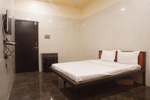 a bedroom with a bed with white sheets and a television at Yashraj Resorts in Pune