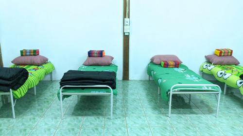 a room with three green beds with pillows on them at ที่ราบสูง & โฮมสเตย์ in Ban Mae Na Tai