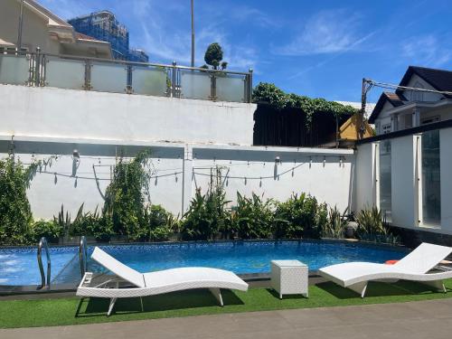 a swimming pool with two white chairs next to a house at Minh Phước Villa 12 Kim Ngân in Vung Tau