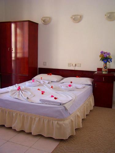 a large bed with white sheets and red flowers on it at Villa Fortin Pension in Kuşadası