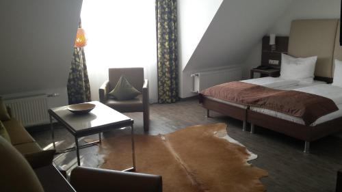 a bedroom with a bed and a chair and a table at Hotel-Restaurant Pfälzer Hof in Edenkoben