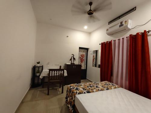 a bedroom with a bed and a table and a ceiling fan at Mundro Arcadia- Petharayil Homestay in Munroe Island