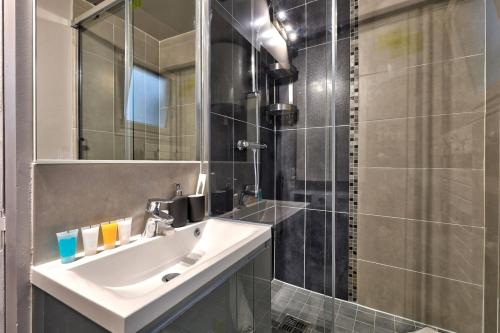 une salle de bain avec un lavabo et une douche avec un miroir dans l'établissement Élégante Suite Haussmannienne au Prestige Parisien, à Paris